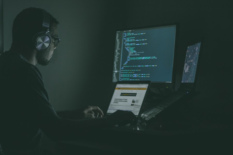Person working on code across two monitors in a dark room